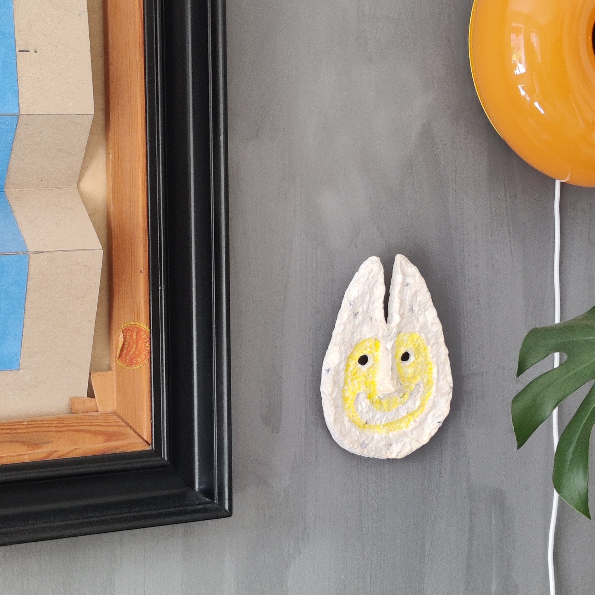 Decorative wall art with a smiley face design on a gray wall.