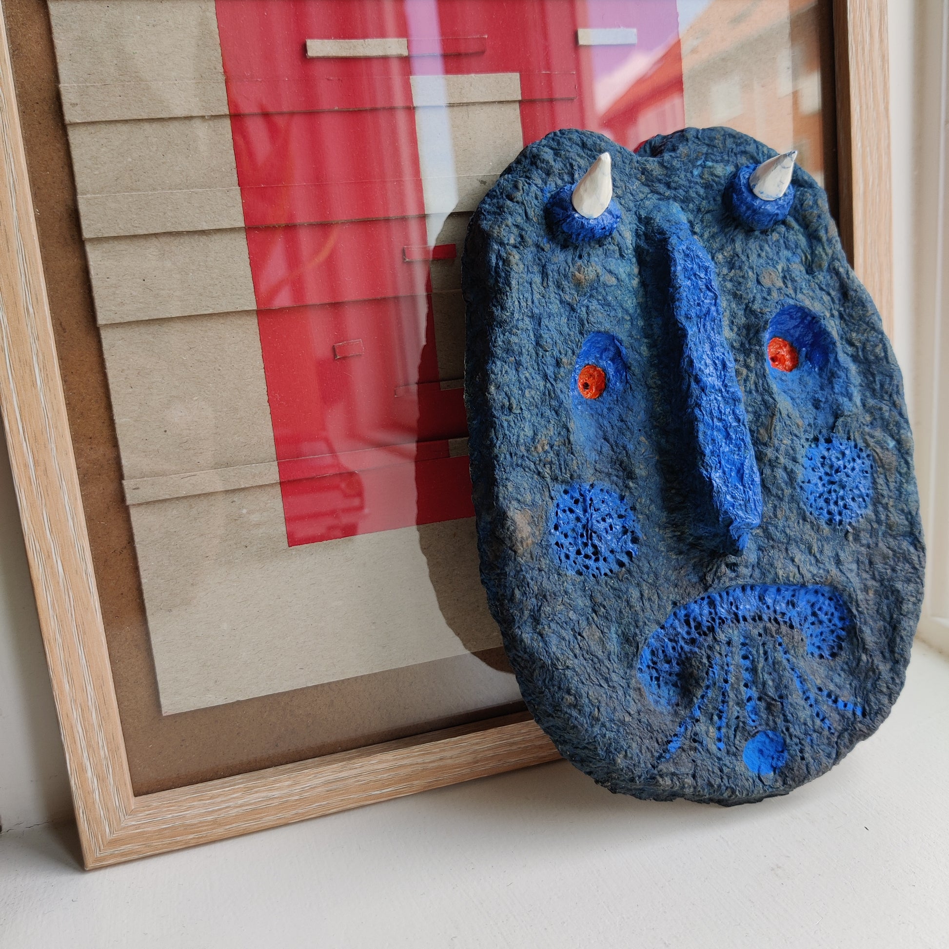 Blue textured object with white and orange accents on a surface next to a framed picture.