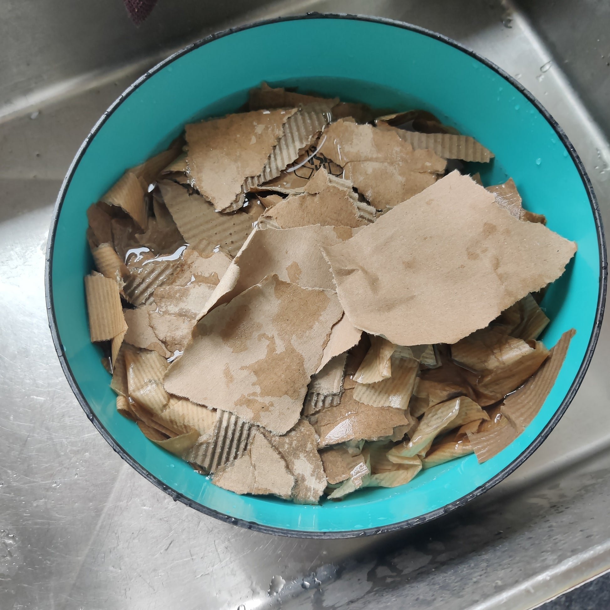 Teal bowl filled with brown paper pieces in water